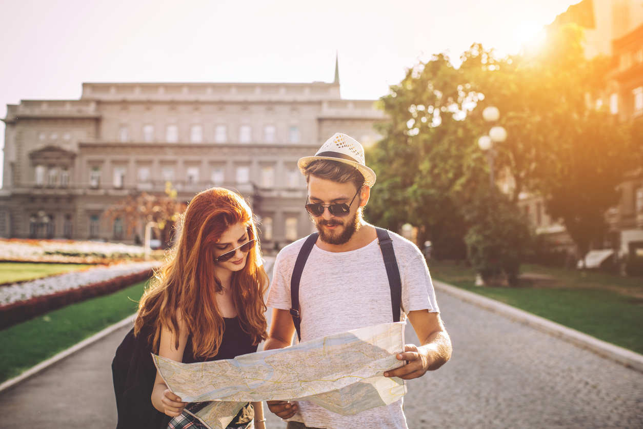  A young couple is looking at a map while walking down a park.